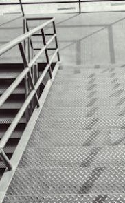 Top view of a modern industrial staircase with metal steps and railings, showcasing geometric patterns.